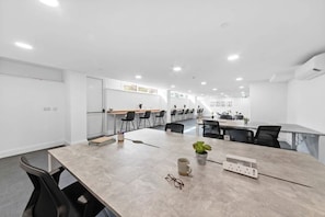 A modern conference room with a long table, multiple chairs, and a potted plant.