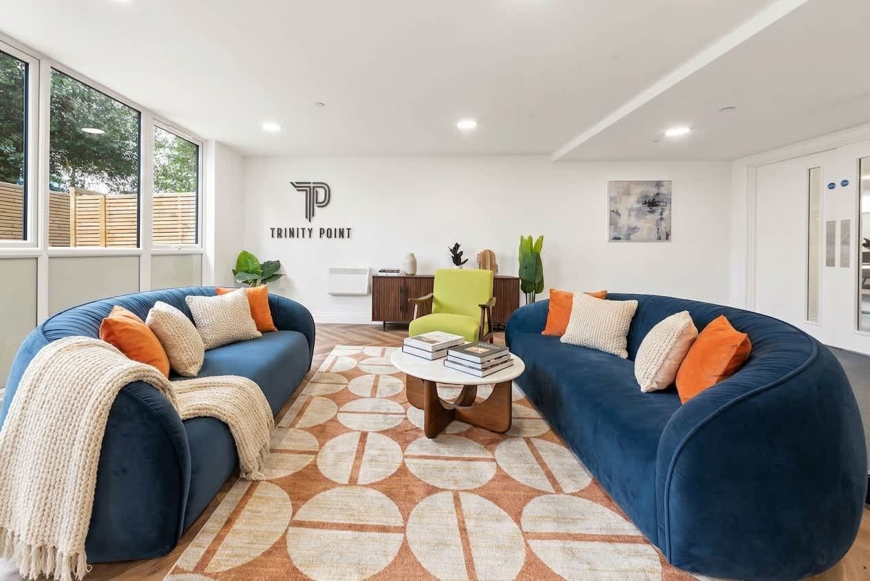 A living room with two blue sofas, a green armchair, and a coffee table with books.