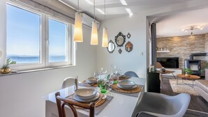 Ein moderner Essbereich mit Meerblick, einem Kamin und einer Steinwand.