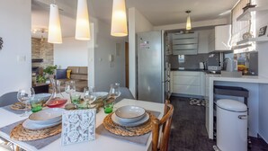 Eine moderne Küche mit Essbereich, ausgestattet mit einem Kühlschrank, Schränken und einem Esstisch, gedeckt mit Tellern, Gläsern und einer Vase.