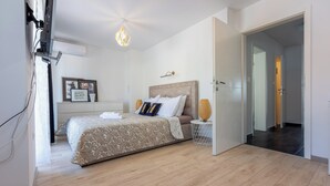 Ein Schlafzimmer mit Bett, Nachttisch, Lampe und Wand-Klimaanlage.