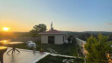 Ein Steinhhaus mit Terrasse, Gartenmöbeln und einem gepflasterten Weg.