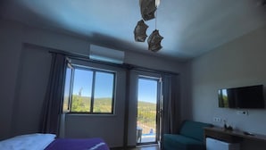 Una camera da letto con un letto, una scrivania, una TV e un balcone con vista.