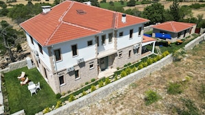 Una casa a due piani con tetto in tegole rosse, pareti in pietra e un muro di sostegno in pietra davanti.