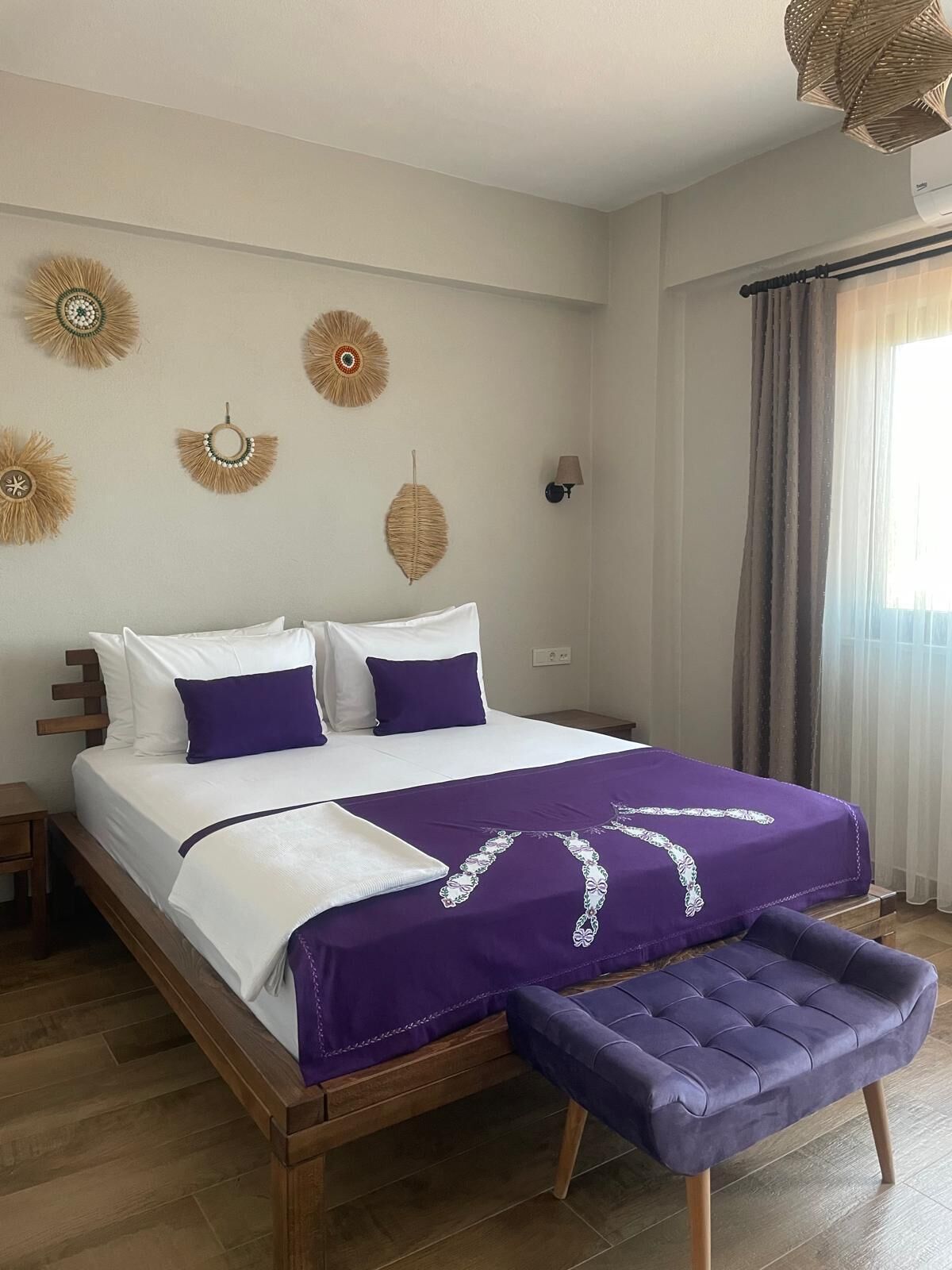 Un dormitorio ordenado con cama, mesitas de noche, un banco y decoración en la pared.