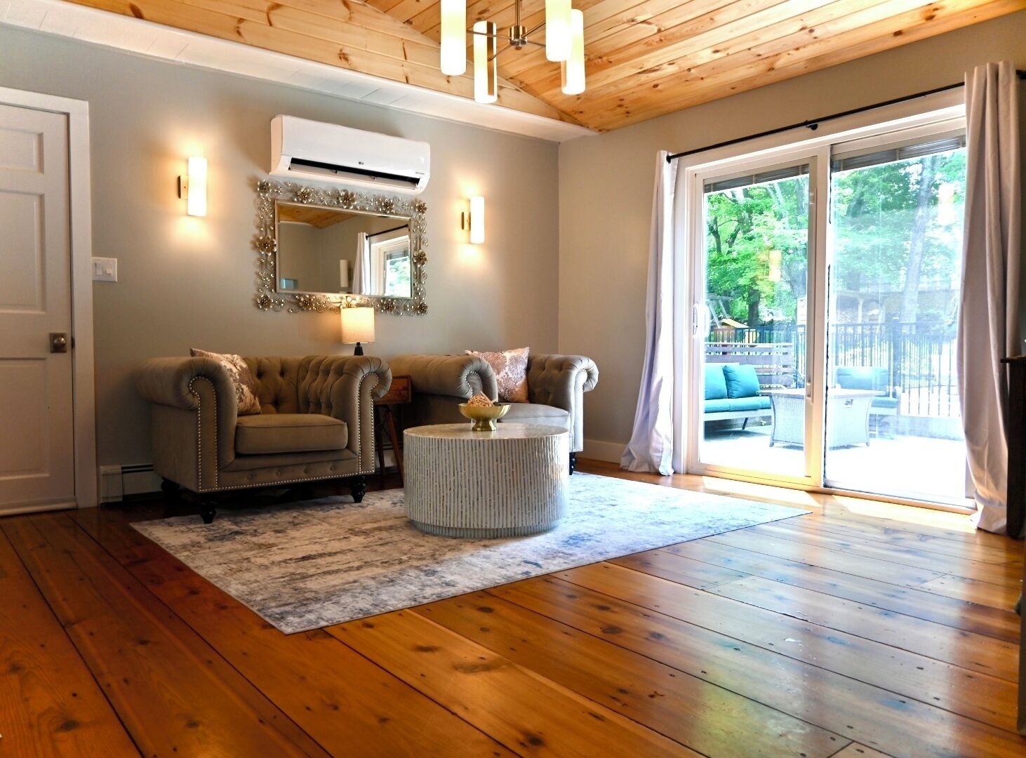 A living room with two sofas, a round coffee table, a mirror, and a sliding glass door to the outdoors.