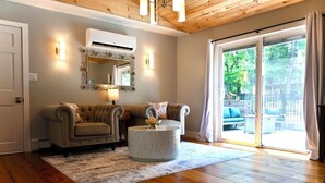 A living room with two sofas, a round coffee table, a mirror, and a sliding glass door to the outdoors.