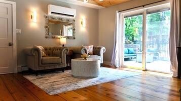 A living room with two sofas, a round coffee table, a mirror, and a sliding glass door to the outdoors.