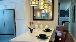 A modern kitchen with a central island, white cabinetry, and pendant lighting.