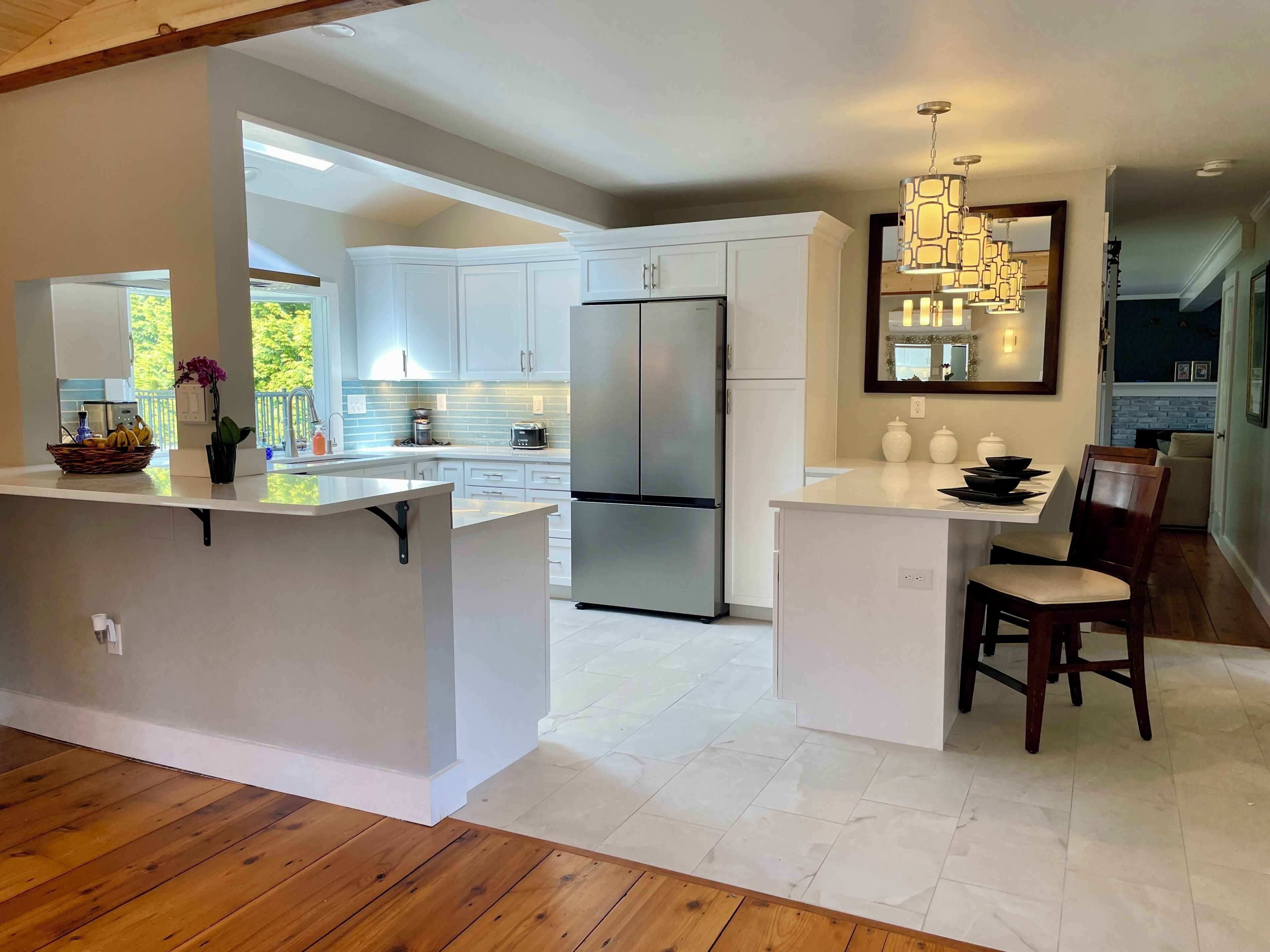 A modern kitchen with white cabinetry, a stainless steel refrigerator, and a central island.