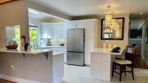 A modern kitchen with white cabinetry, a stainless steel refrigerator, and a central island.