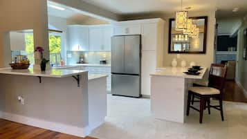 A modern kitchen with white cabinetry, a stainless steel refrigerator, and a central island.