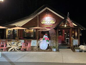 Ein Blockhaus mit einem Schild 'Moonridge Coffee Company', einer Schneemann-Dekoration und einer Holzveranda mit roten Stühlen.