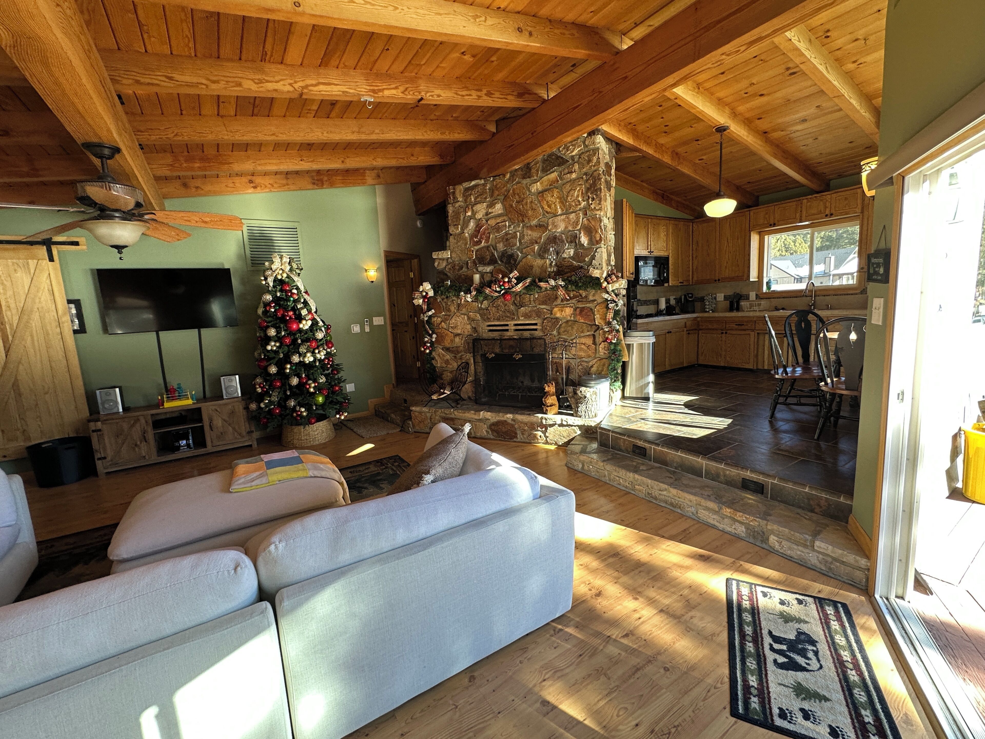 A cozy living room with a fireplace, a television, and a Christmas tree.