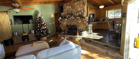 A cozy living room with a fireplace, a television, and a Christmas tree.