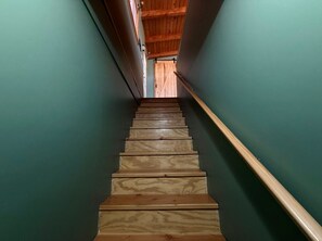 Eine Holztreppe mit Handlauf, die zu einer Tür am oberen Ende führt.