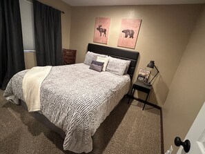 Ein Schlafzimmer mit einem großen Bett, einem Nachttisch, einer Lampe und zwei Wandbildern.