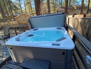 Ein Whirlpool mit Bedienfeld, umgeben von einer Holzdielen-Terrasse und einem Holzzaun.