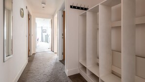 A hallway with a coat rack, a clock, and a door leading to another room. - Square Green (No 15) | Balcony (St Andrews)