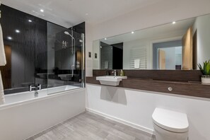 Ein modernes Badezimmer mit einer Duschkabine, einem weißen Waschbecken und einer Toilette.