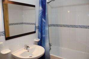 A bathroom with a sink, mirror, shower, and tiled walls. - 2 Bedroom Apartment (MOJACAR)