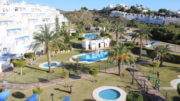 A resort with multiple swimming pools, palm trees, and a hillside view. - 2 Bedroom Apartment (MOJACAR)
