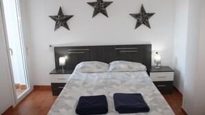 A bedroom with a bed, two bedside tables, a nightstand, and three wall-mounted stars. - 2 Bedroom Apartment (MOJACAR)