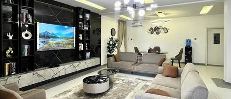 A modern living room with a flat-screen TV, a round coffee table, and a sofa set.