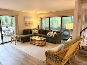 A living room with a sectional sofa, a coffee table, and a wicker chair. - Sea Colony Townhome: Walk to Private Beach, Pools & Tennis (Bethany Beach)