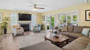 A living room with a fireplace, sofa, armchair, and a television. - 29532 N. Cotton Way - Cotton Patch East (Bethany Beach)