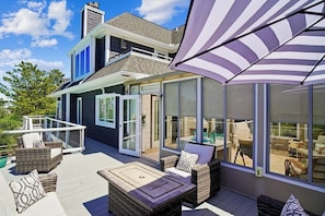 Ein modernes Haus mit überdachter Terrasse, Gartenmöbeln und großen Fenstern.