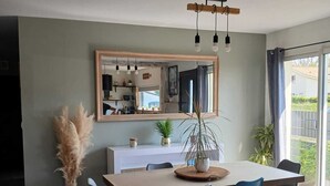 Un comedor con una mesa grande, sillas, un espejo y una planta en maceta.