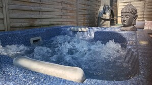 Un jacuzzi con valla de madera y una estatua de Buda al fondo.