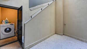 A laundry area with a washing machine, detergent bottles, and a drying rack. - FindMe inPorto Bonfim 0F (Porto)