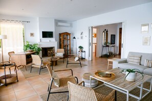 Ein geräumiges Wohnzimmer mit Kamin, Sitzgruppe und Fernseher.