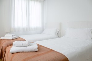 A hotel room with two beds, each with white linens and a brown headboard. There are folded towels on the beds. - Casa Barbara - Harbor view (Es Castell)