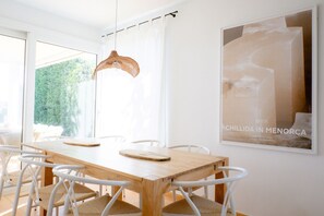 En matplats med ett träbord, vita stolar och en hängande lampa.