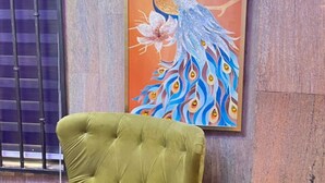 Un sillón verde en una habitación con un cuadro de un pavo real en la pared.
