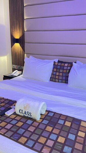A hotel room with a bed, a nightstand with a phone, and a towel with 'CLASS' on it. - Class Suites Residence (Lagos)