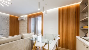 Une cuisine moderne avec une table à manger en verre, des chaises blanches et un lambris en bois.