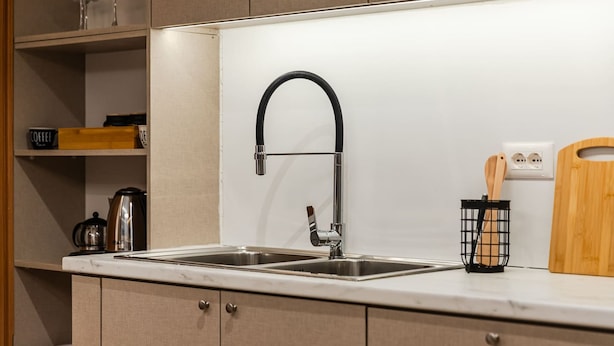 Une cuisine moderne dotée d’un évier en acier inoxydable, de meubles en bois et d’une planche à découper posée sur le plan de travail.
