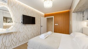 Une chambre d’hôtel avec un lit, une télévision, un miroir, un mur recouvert de panneaux de bois et un lustre.