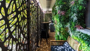 A narrow corridor with a black perforated partition, a wooden bench, and a vertical garden wall. - ISLAND GARDEN DESIGN HOUSE (Milano)