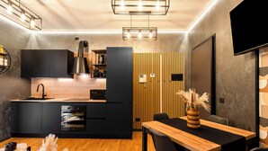 A modern kitchen with a built-in oven, a wooden dining table, and a black chair. - ISLAND GARDEN DESIGN HOUSE (Milano)