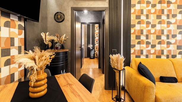 A modern hotel lobby with a wooden reception desk, a sofa, a TV, and a patterned wall. - ISLAND GARDEN DESIGN HOUSE (Milano)