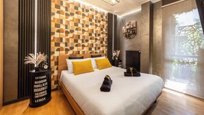 A modern hotel room with a large bed, a headboard with a geometric pattern, a bedside table with a vase, and a view of greenery outside. - ISLAND GARDEN DESIGN HOUSE (Milano)