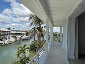 Ein Balkon mit Blick auf einen Yachthafen, Palmen und Gebäude am Wasser.