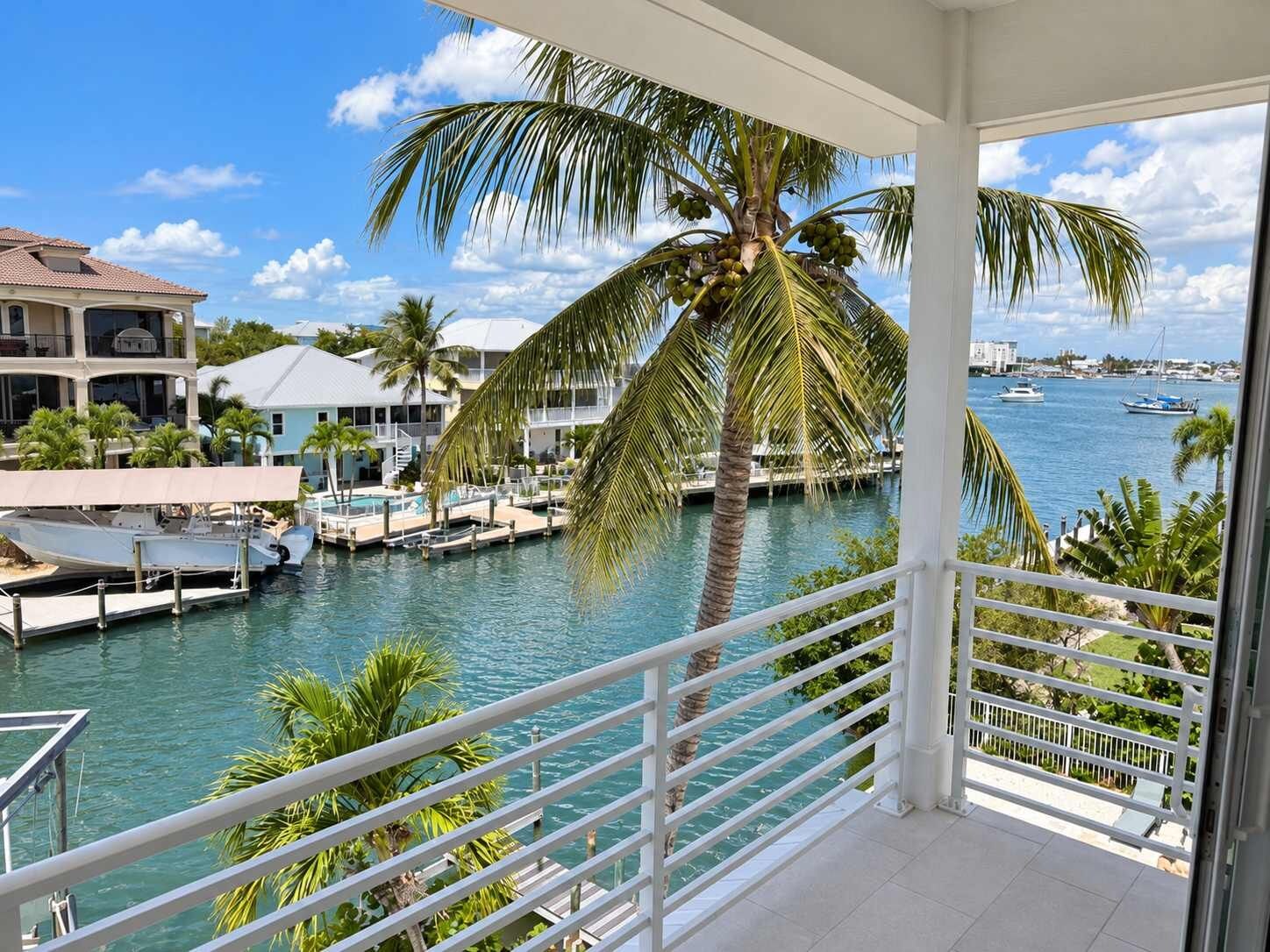 A balcony with a view of a marina, boats, and a palm tree.