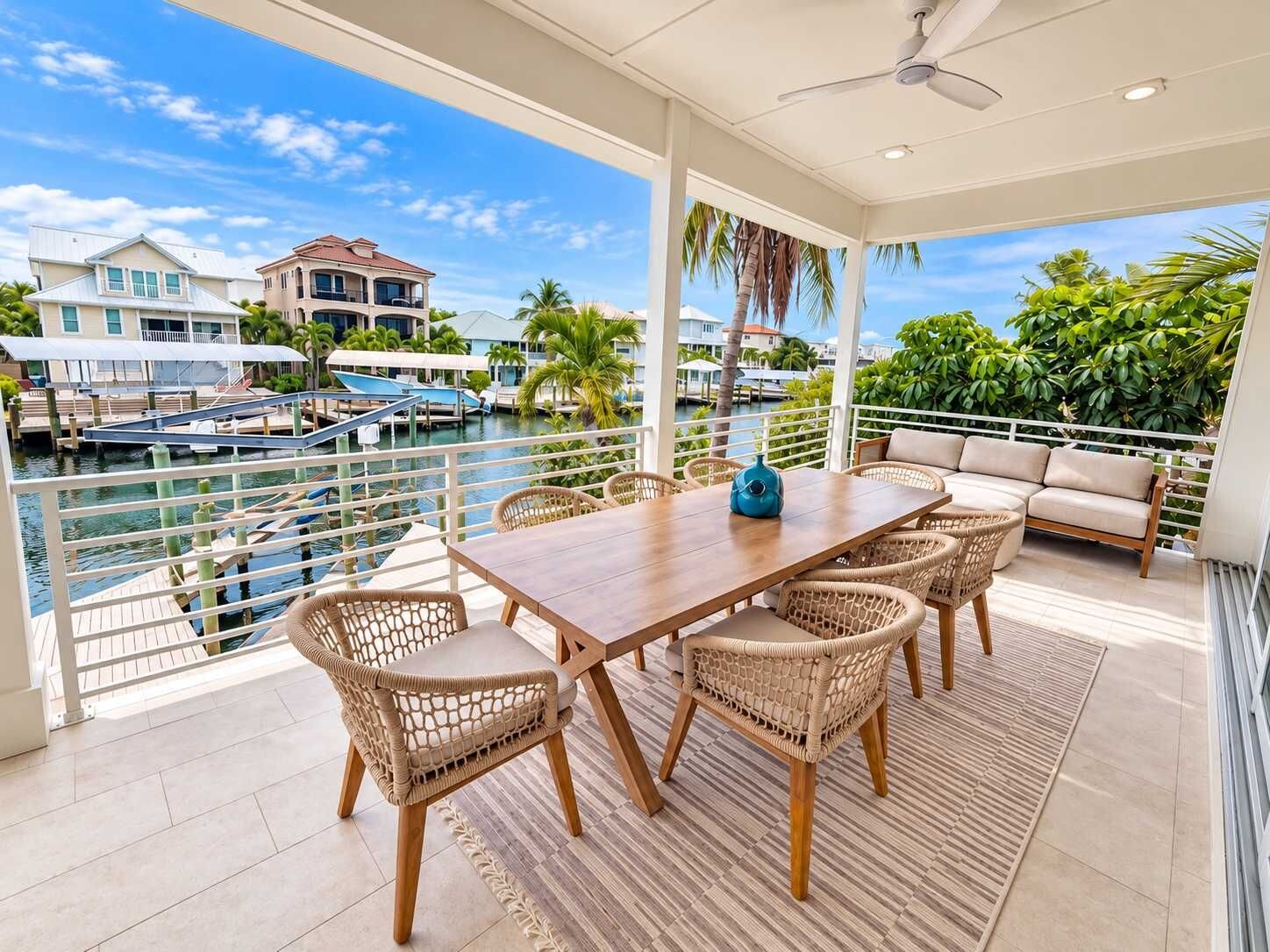 A covered outdoor dining area with a view of a marina and buildings.