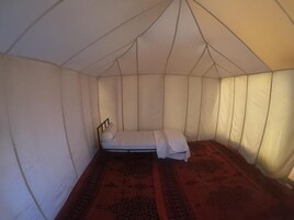 Una tienda de campaña con cama, colchón y cabecera.